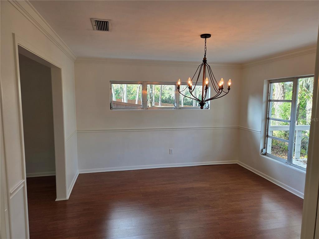 2901 Southwest 4 Court Gainesville, FL 32601 - Photo 35 of 58 an empty room with wooden floor chandelier and windows