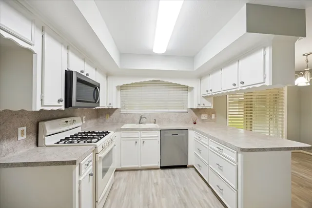a kitchen with stainless steel appliances granite countertop a stove a sink and a microwave
