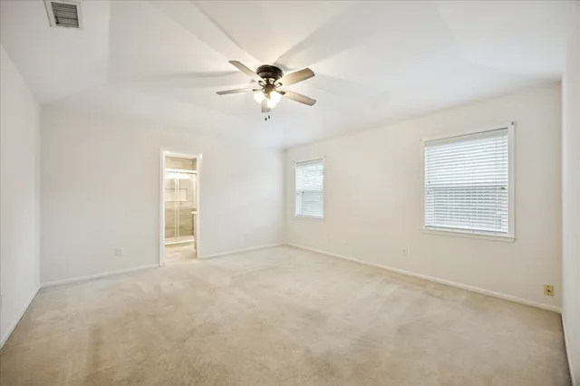 an empty room with windows and fan