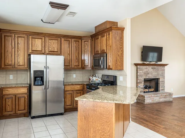 a kitchen with stainless steel appliances granite countertop a refrigerator a stove a sink dishwasher and wooden cabinets