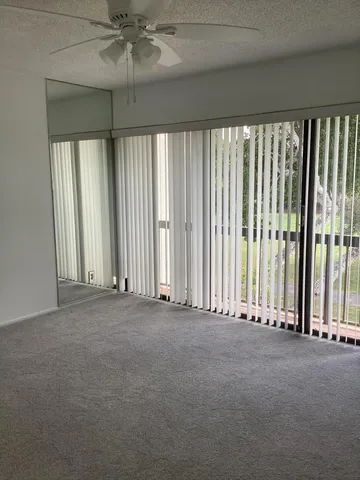 an empty room with windows and a chandelier fan