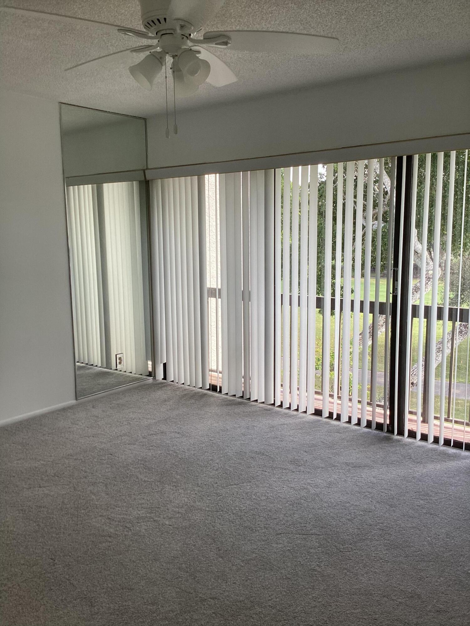 2308 Bridgewood Drive, Unit 2308 Boca Raton, FL 33434 - Photo 23 of 42 an empty room with windows and a chandelier fan