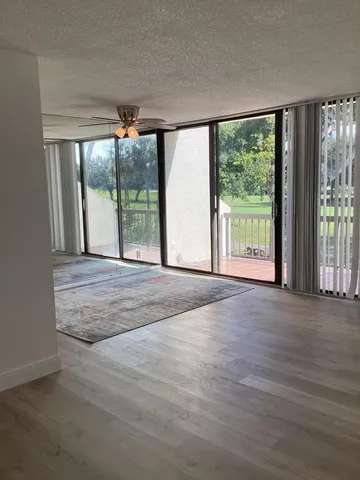 a view of an empty room with wooden floor and a floor to ceiling window
