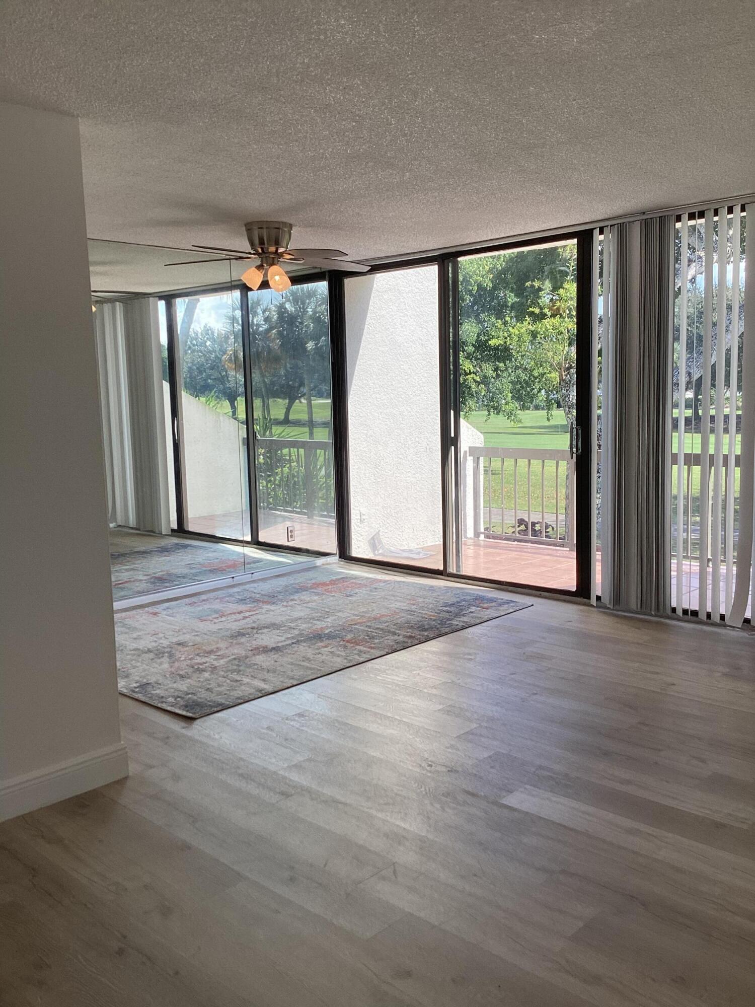 2308 Bridgewood Drive, Unit 2308 Boca Raton, FL 33434 - Photo 8 of 42 a view of an empty room with wooden floor and a floor to ceiling window