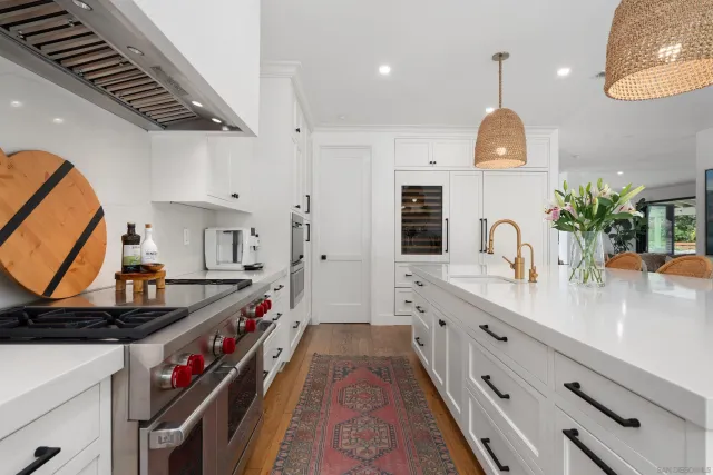a very nice looking room with kitchen island white cabinets and a wooden floor