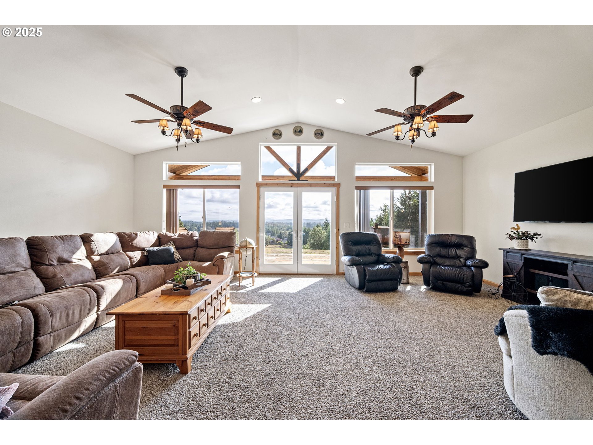 24674 Bolton Hill Road Veneta, OR 97487 - Photo 11 of 48 a living room with furniture a ceiling fan a flat screen tv and a large window