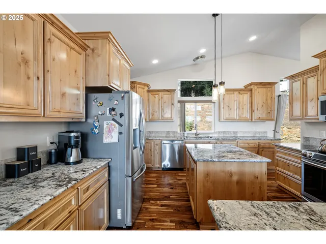 a kitchen with stainless steel appliances granite countertop a refrigerator a sink a stove and oven