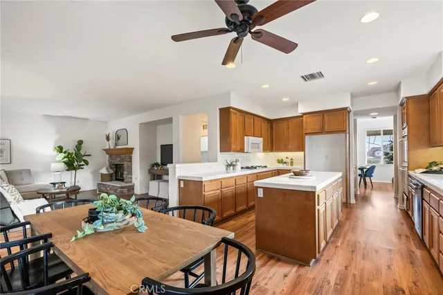 a kitchen with stainless steel appliances granite countertop a stove top oven a refrigerator a dining table and chairs with wooden floor