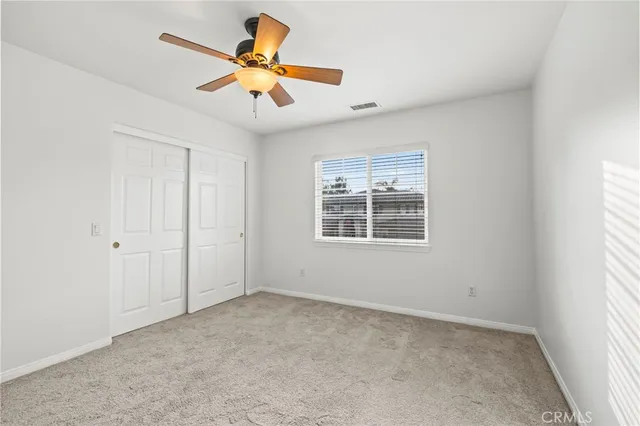 an empty room with a window and a fan