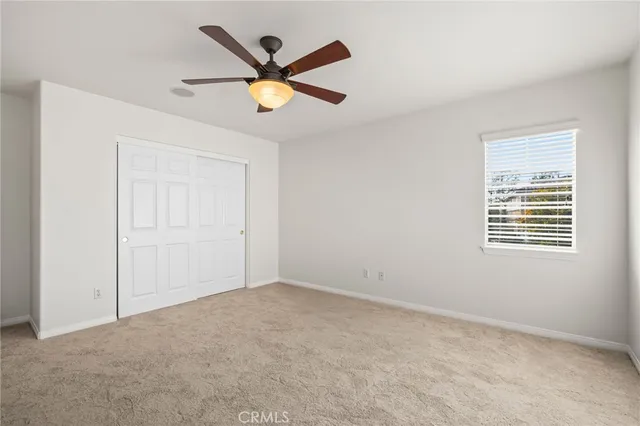 an empty room with ceiling fan and window
