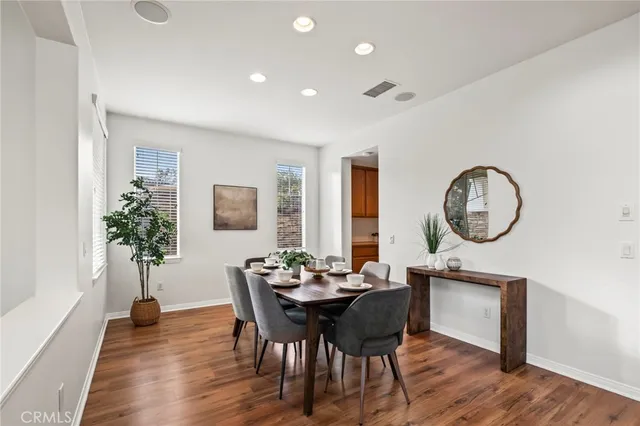 a dining room with furniture a potted plant and wooden floor