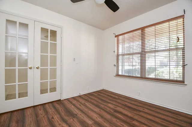 a view of an empty room with a window and wooden floor
