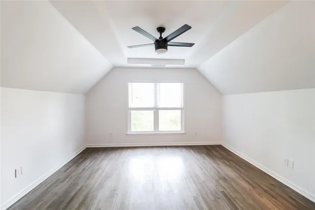an empty room with wooden floor a ceiling fan and windows