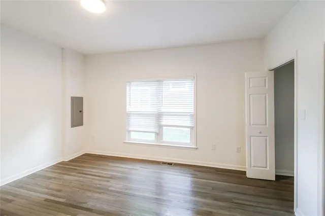 an empty room with wooden floor and windows