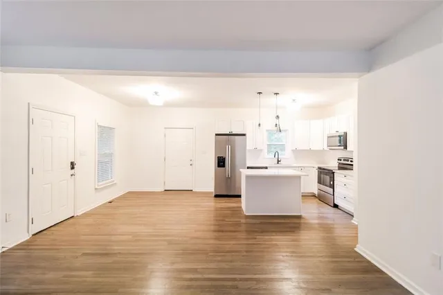 a view of a kitchen with kitchen island stainless steel appliances wooden floor and view living room
