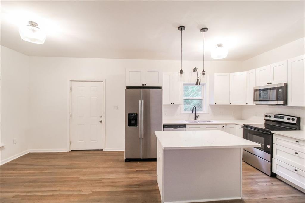 1070 4th Street Northwest Atlanta, GA 30318 - Photo 9 of 21 a kitchen with stainless steel appliances kitchen island granite countertop a sink a stove a refrigerator and island with wooden floor