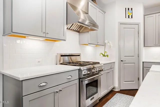 a kitchen with stainless steel appliances kitchen island granite countertop a refrigerator a sink dishwasher a stove and white cabinets with wooden floor