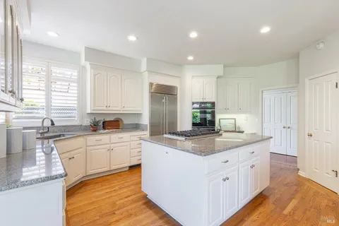 a kitchen with white cabinets sink and window