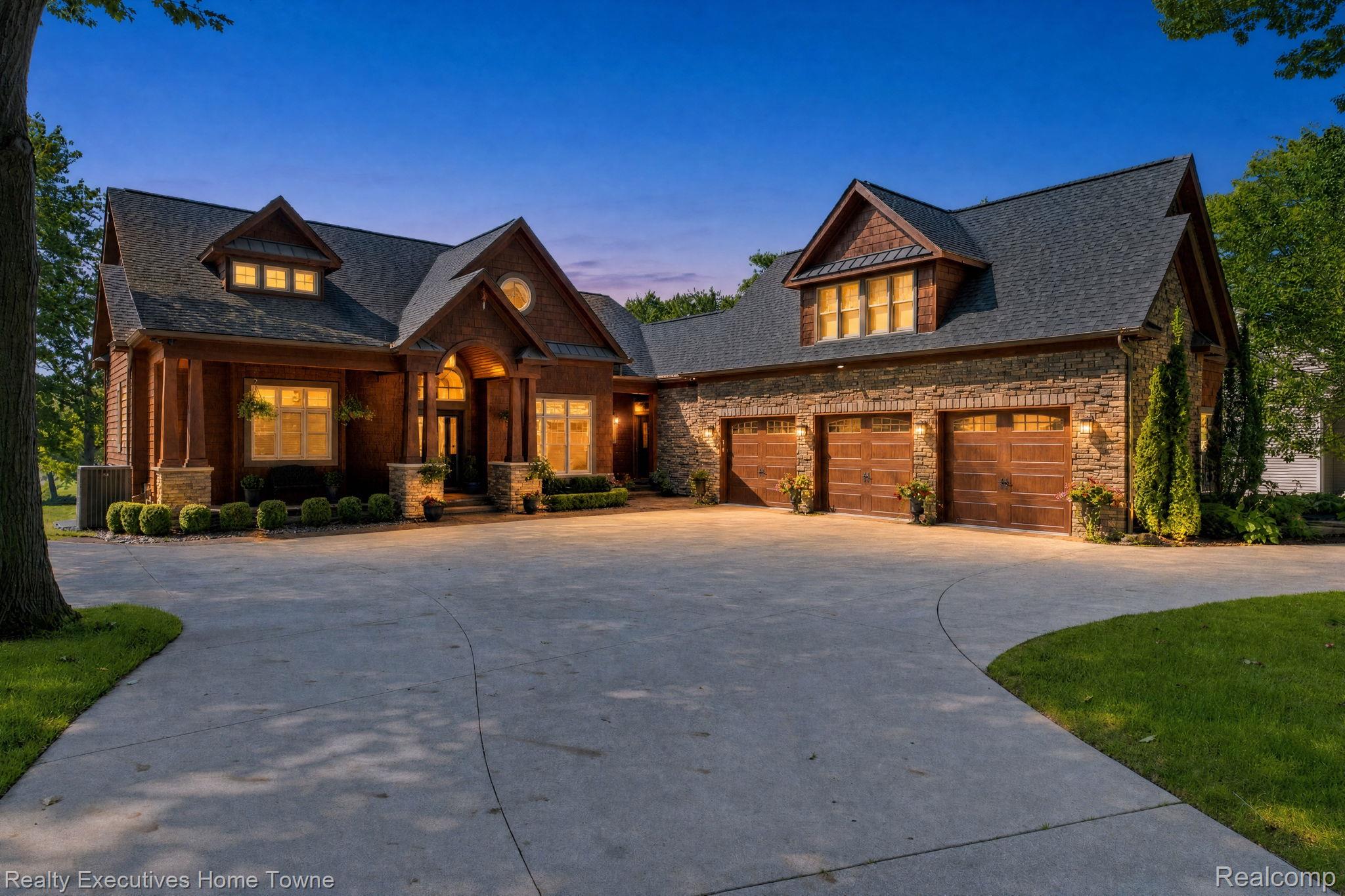 2829 Riverside Drive Port Huron, MI 48060 - Photo 1 of 99 Craftsman-style residence featuring a stone and wood facade, multiple gables, a three-car garage with wood-finish doors, and a circular driveway