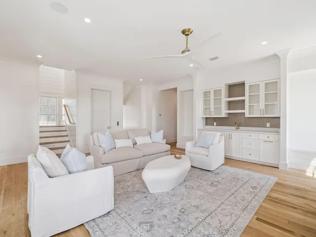 a living room with furniture a large window and kitchen view