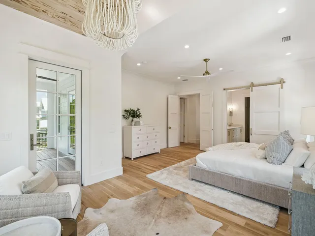 a spacious bedroom with a bed a chandelier and couch