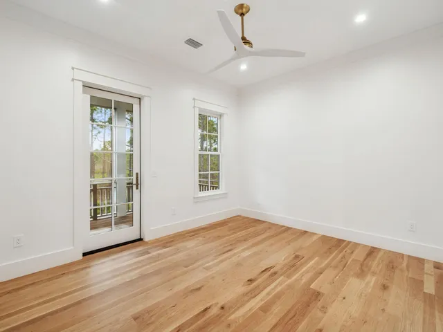 an empty room with wooden floor cabinet and windows