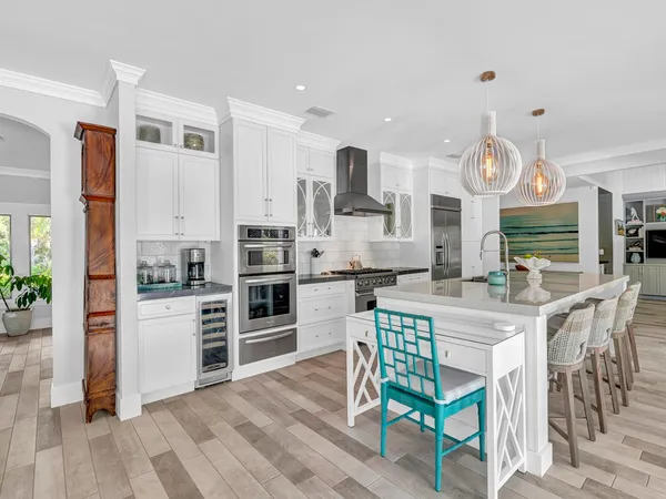 a kitchen with stainless steel appliances a stove a refrigerator and a dining table with wooden floor