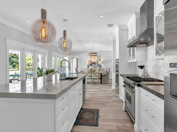 a large kitchen with kitchen island granite countertop a stove a large window cabinets and a chandelier