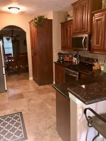 a kitchen with granite countertop a stove top oven and cabinets
