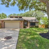 a view of a house with a yard and a large tree