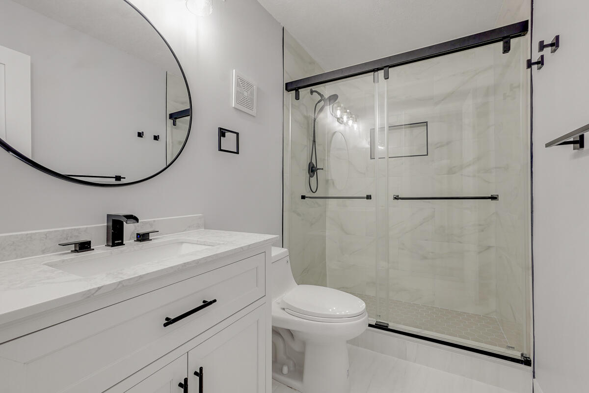 15072 Ashland Place, Unit 132 Delray Beach, FL 33484 - Photo 14 of 38 a bathroom with a sink mirror toilet and shower