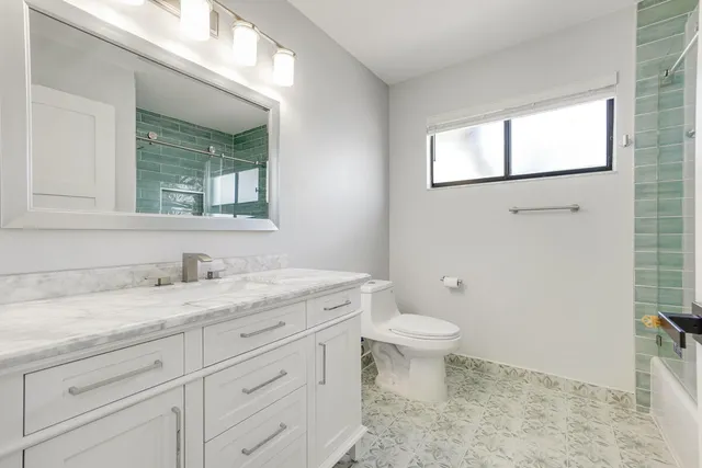 a bathroom with a granite countertop sink a toilet and a mirror
