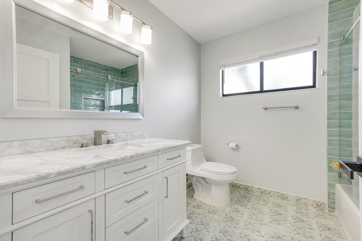 15072 Ashland Place, Unit 132 Delray Beach, FL 33484 - Photo 19 of 38 a bathroom with a granite countertop sink a toilet and a mirror