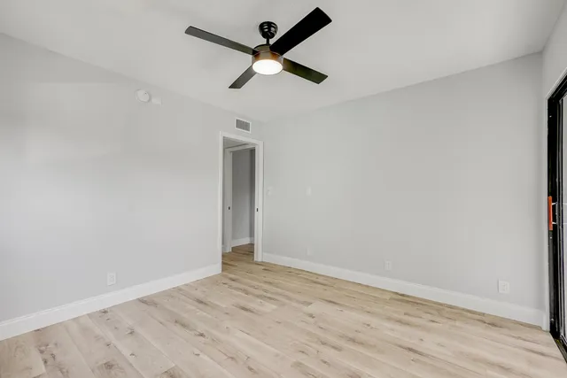 an empty room with wooden floor and ceiling fan