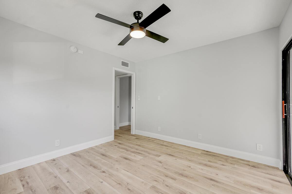 15072 Ashland Place, Unit 132 Delray Beach, FL 33484 - Photo 21 of 38 an empty room with wooden floor and ceiling fan
