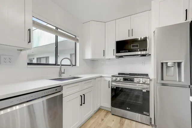 a kitchen with white cabinets stainless steel appliances and sink