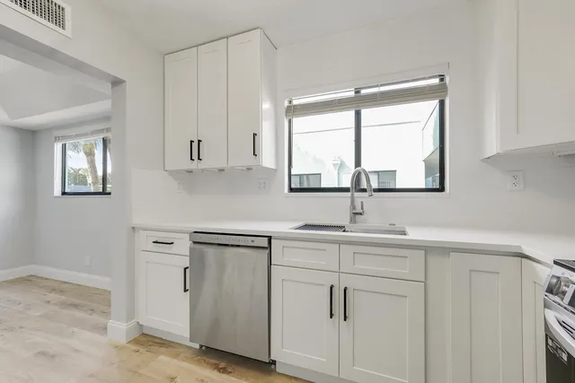 a kitchen with white cabinets and a window