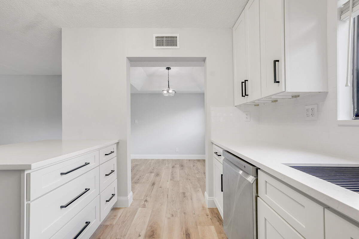 15072 Ashland Place, Unit 132 Delray Beach, FL 33484 - Photo 5 of 38 a kitchen with white cabinets and wooden floor