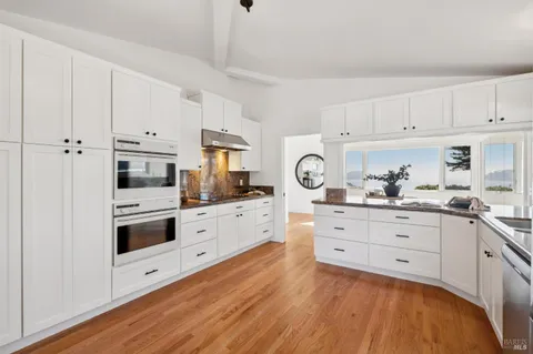 a kitchen with cabinets stainless steel appliances a sink and wooden floor
