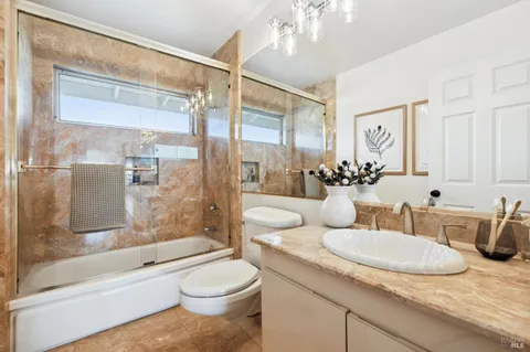 a bathroom with a granite countertop sink toilet tub and shower