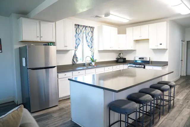 a kitchen with stainless steel appliances granite countertop a sink a refrigerator and a white cabinets