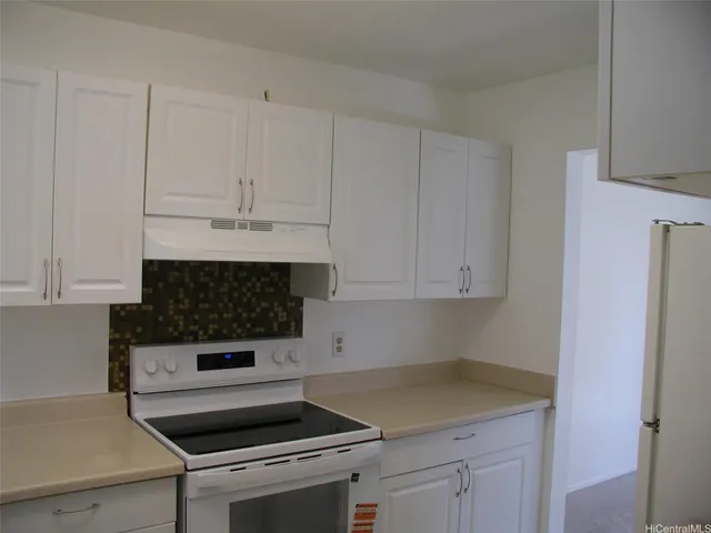 a kitchen with a stove and white cabinets
