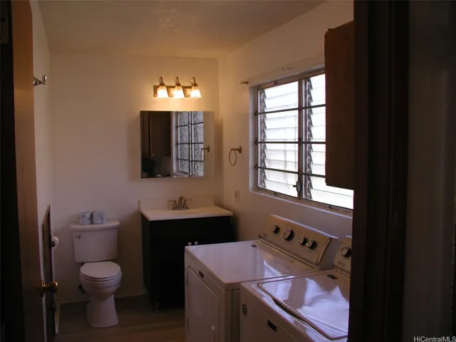 a bathroom with a toilet sink vanity and mirror