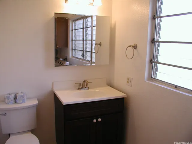 a bathroom with a sink toilet a mirror and window