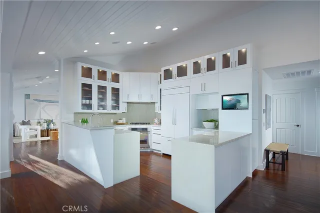a large white kitchen with cabinets and wooden floor