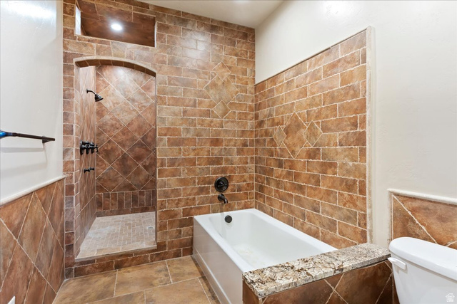 246 Woods Creek Road Morgan, UT 84050 - Photo 50 of 69 Tiled shower enclosure with an arched entry, a built-in niche, and a separate bathtub with a stone cap