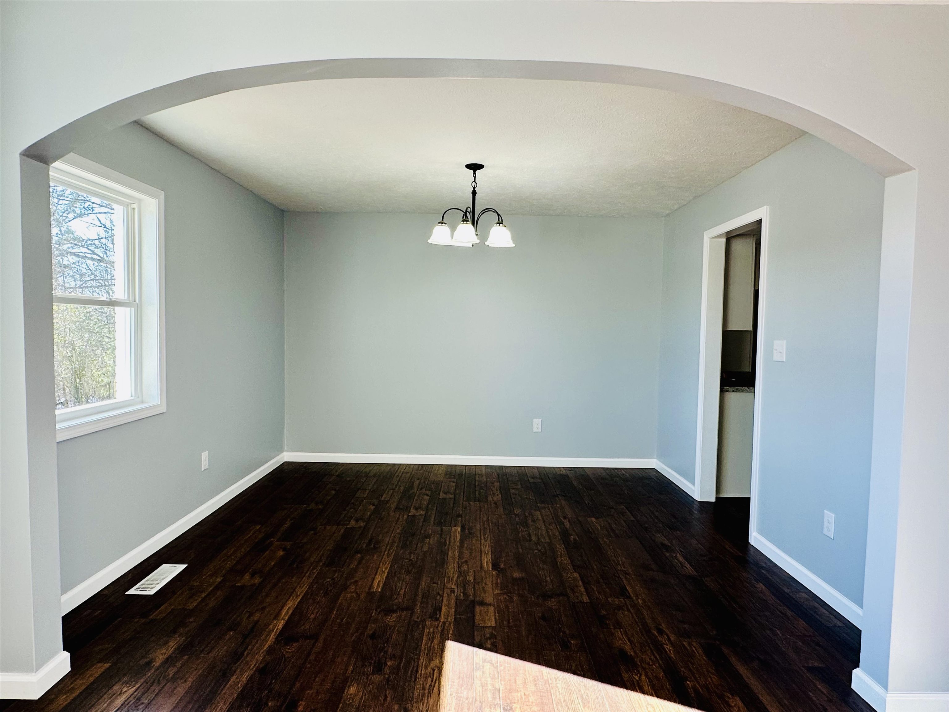 2317 Higginbottom Road Selmer, TN 38375 - Photo 11 of 20 Empty room featuring arched walkways, dark wood finished floors, visible vents, and baseboards