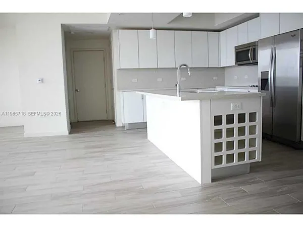 a kitchen with kitchen island a refrigerator and a sink