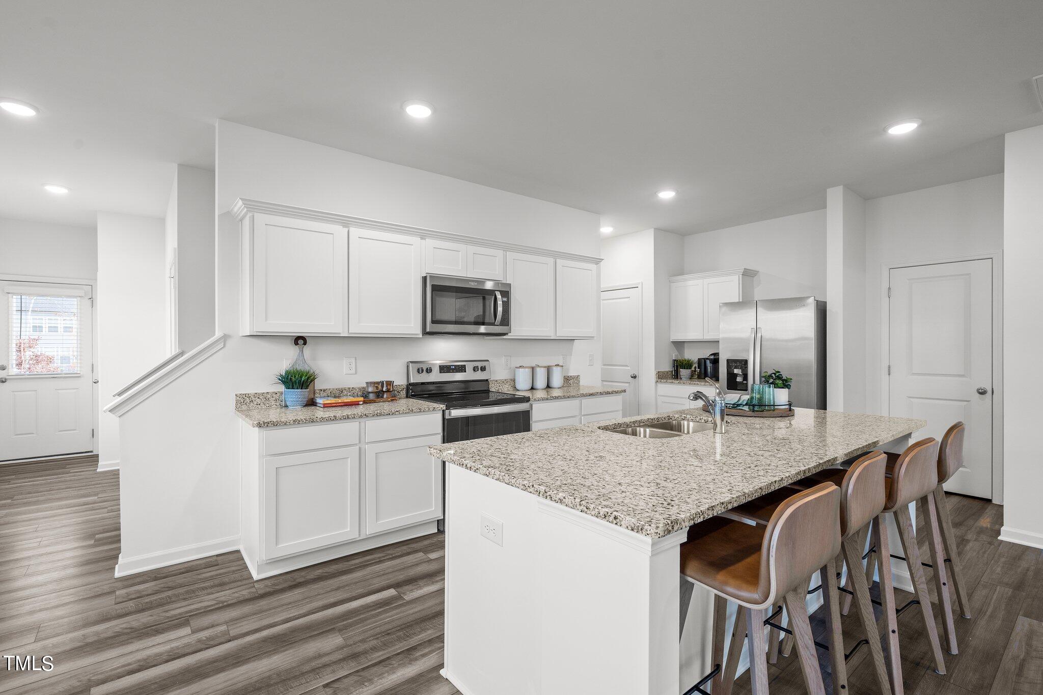 326 Spaight Acrs Way Wake Forest, NC 27587 - Photo 5 of 39 a kitchen with stainless steel appliances granite countertop a stove top oven a sink dishwasher and a refrigerator with wooden floor