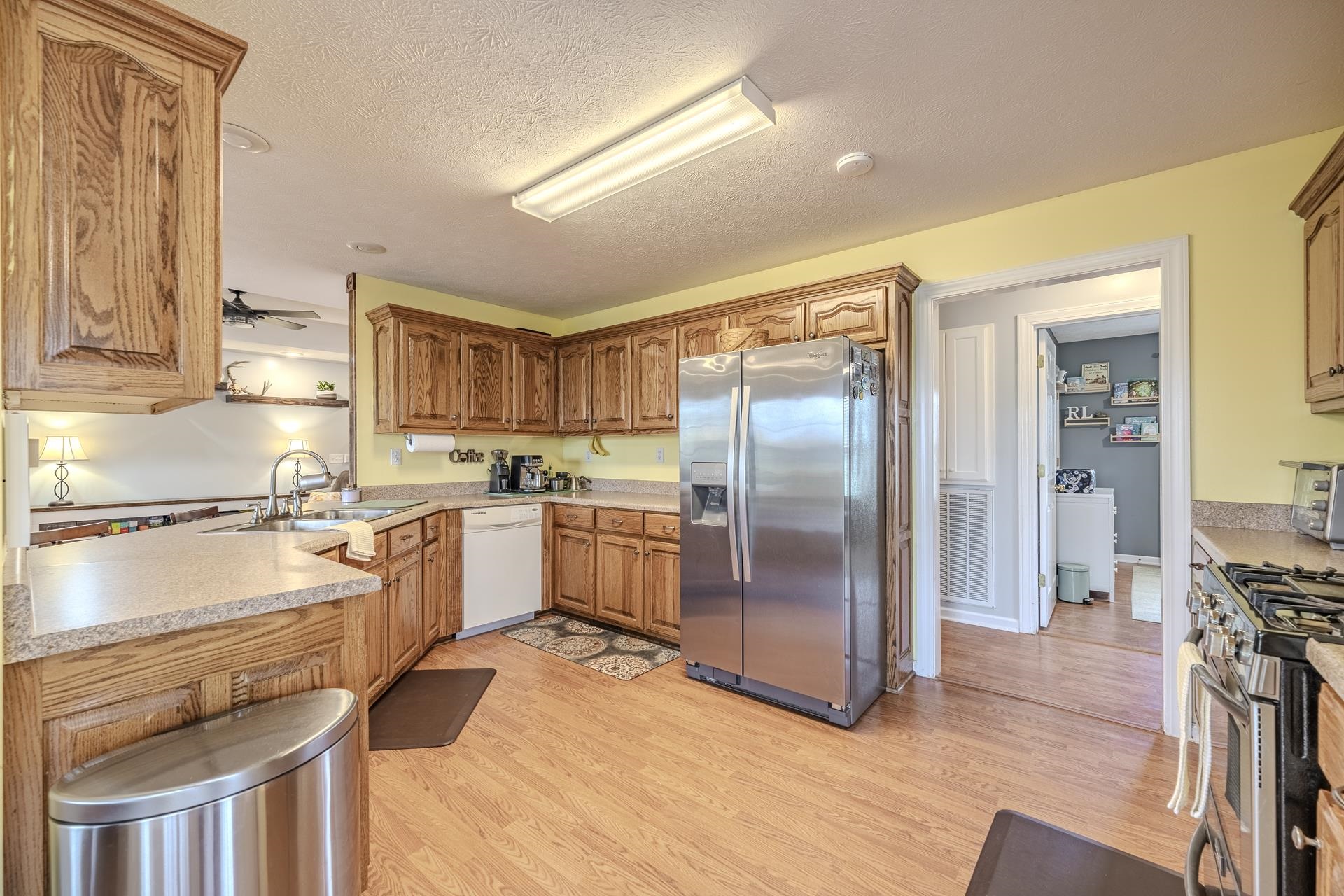 270 2 Boys Road Savannah, TN 38372 - Photo 11 of 35 Kitchen with stainless steel appliances, light countertops, light wood finished floors, ceiling fan, and a textured ceiling